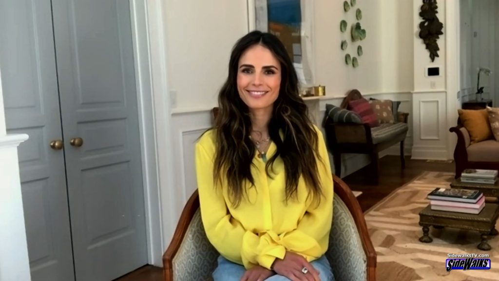 Jordana Brewster sitting in a chair and wearing a yellow top.