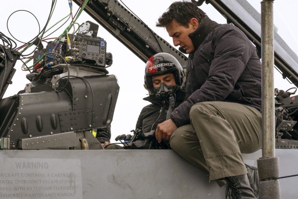 Monica Barbaro and Tom Cruise sitting in a plane